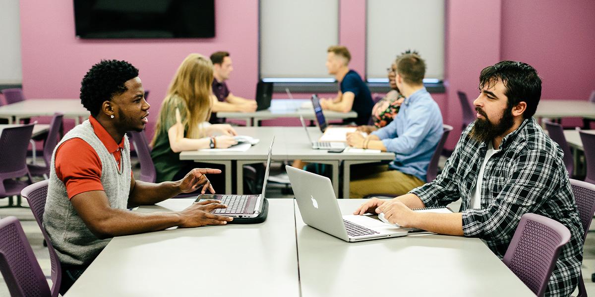 students smiling while sitting in desks in a in classroom