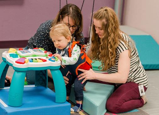 physical 治疗 student and professor work with toddler learning to walk